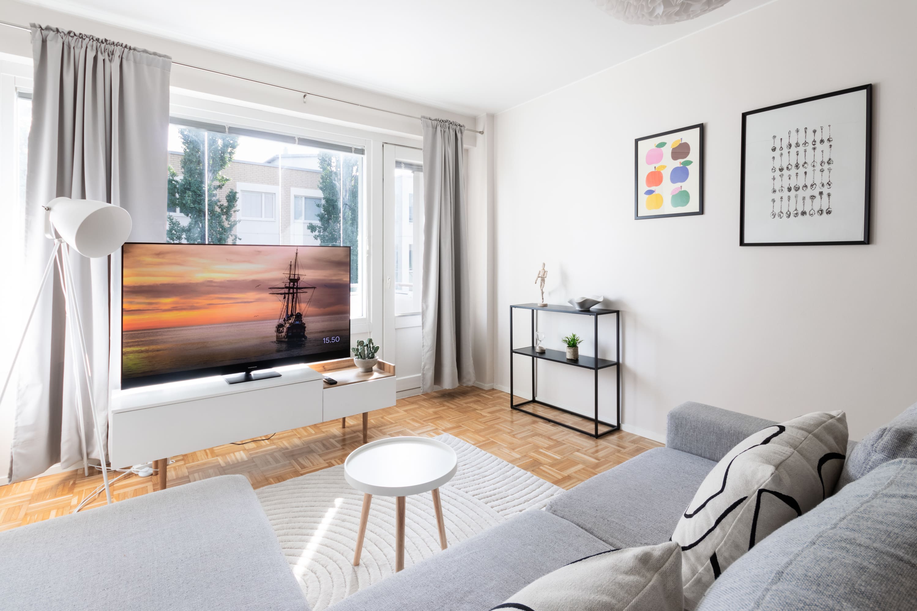 Asuntokuvaus olohuoneesta, jossa televisio ja moderni sisustus, luonnonvalo, pehmeät värit ja viihtyisä tunnelma.