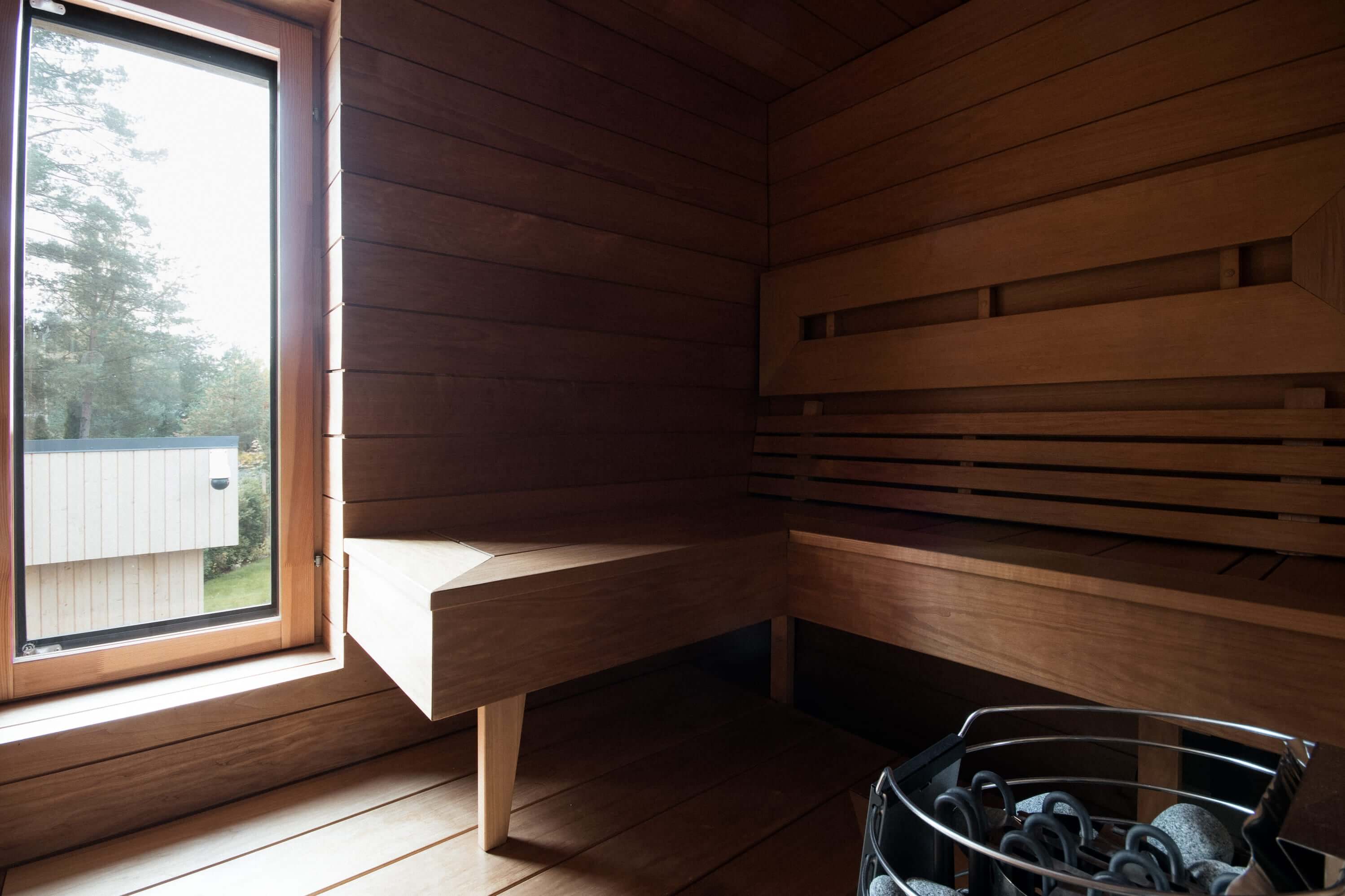 Asuntokuvaus sauna interior with wooden benches and large window.