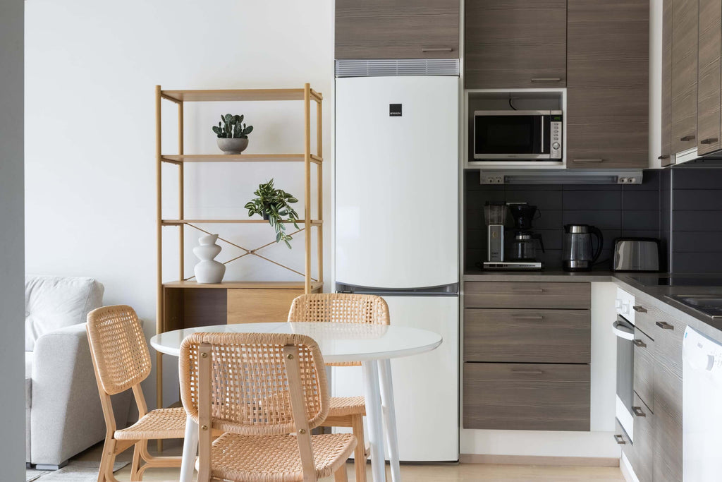 Asuntokuvaus: moderni keittiö, jossa valkoinen jääkaappi, kahviautomaatti ja puu- ja muovikalusteet.