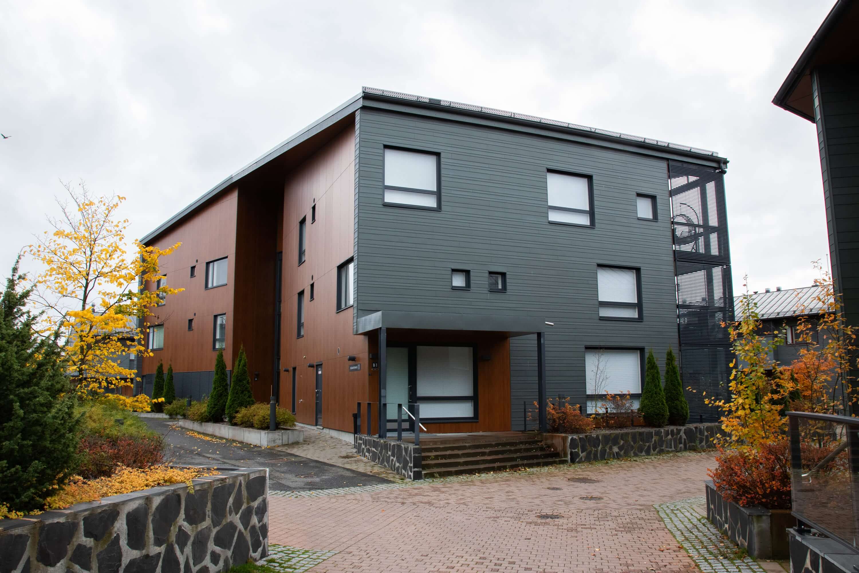 Asuntokuvaus modernista rakennuksesta syksyisessä maisemassa.