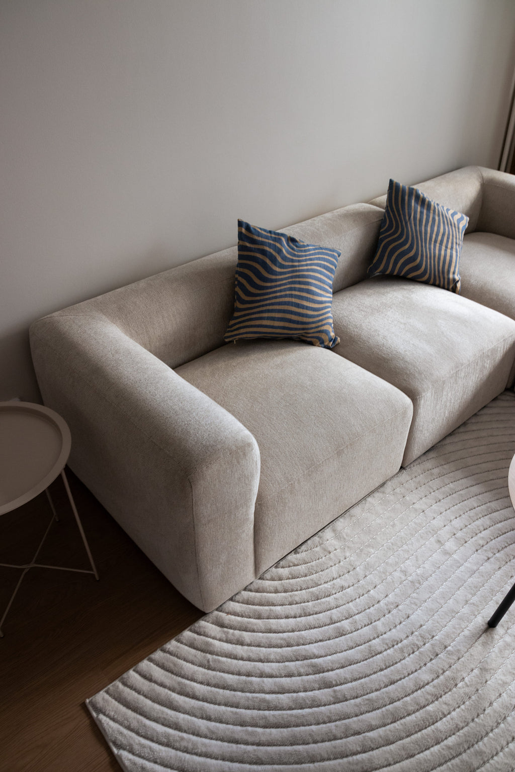 Asuntokuvaus - moderni beige sohva, jossa siniraitaiset tyynyt, sisustuskuvaus