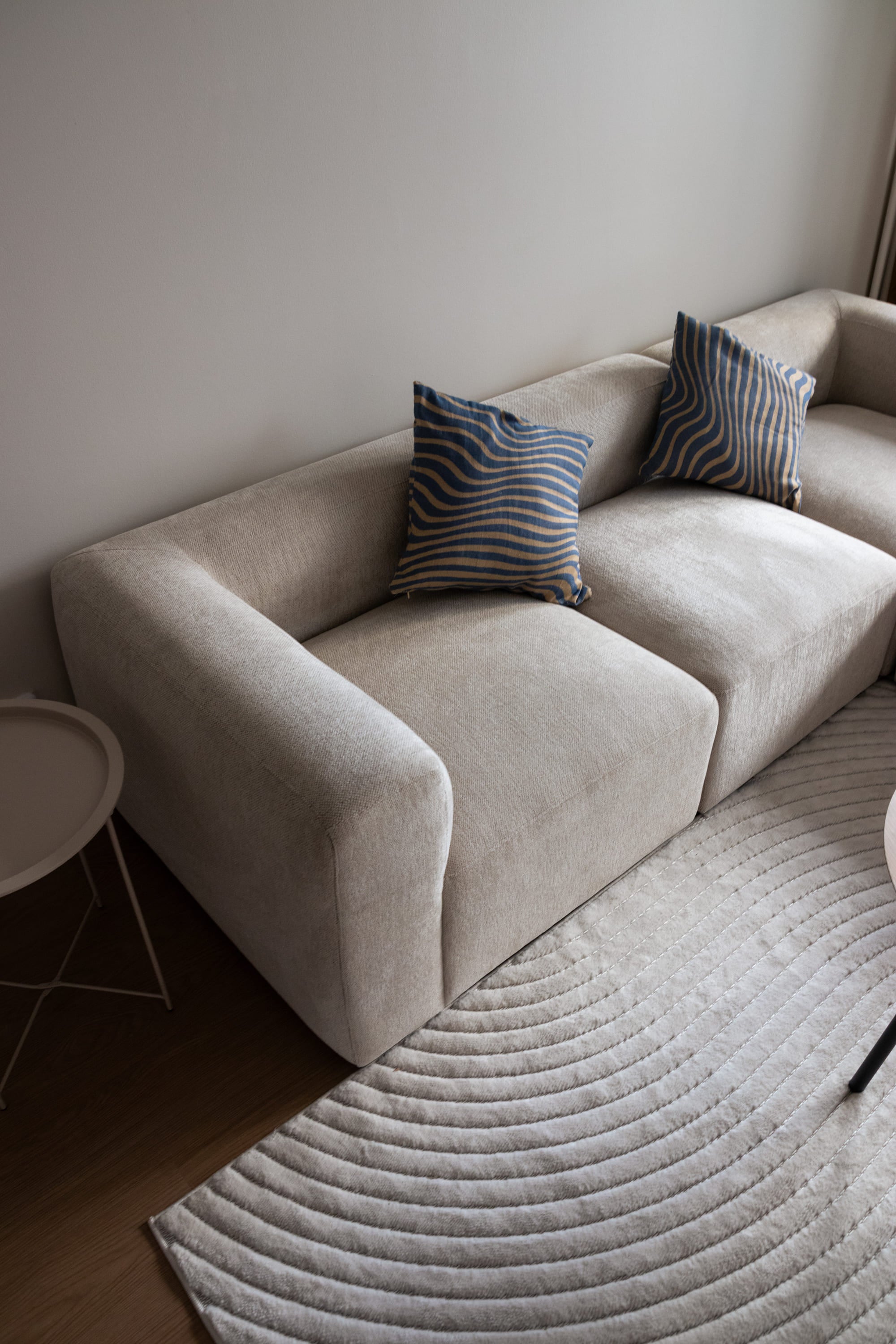 Asuntokuvaus - moderni beige sohva, jossa siniraitaiset tyynyt, sisustuskuvaus